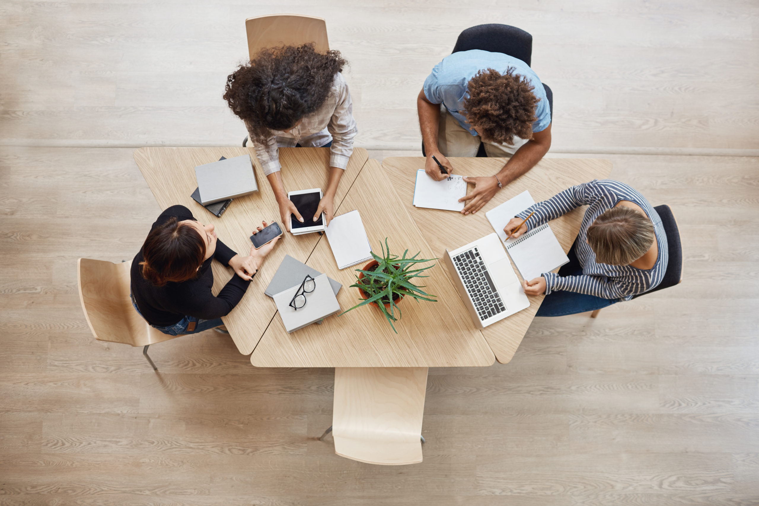 View from above. Business,startup, teamwork concept. Startup partners sitting at coworking space talking about future project, looking through examples of work on laptop and digital tablet